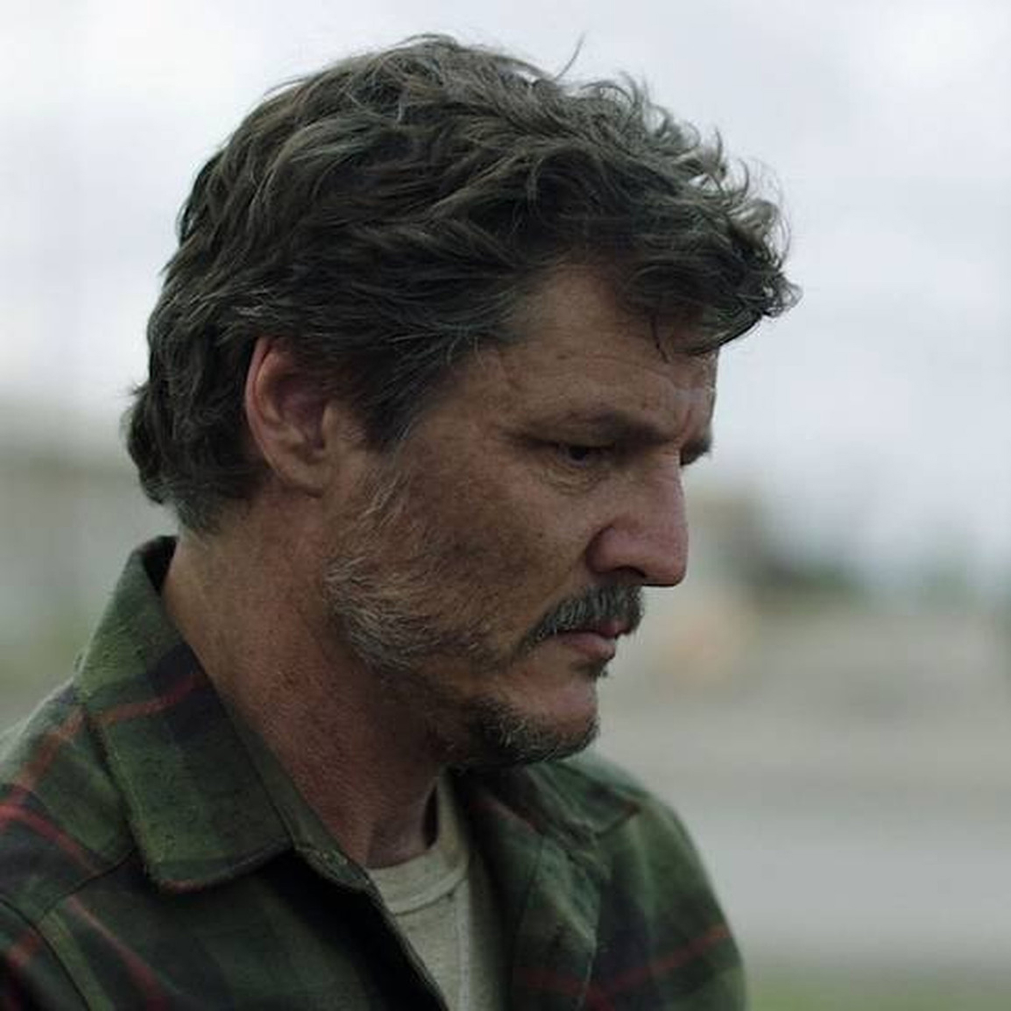 Pedro Pascal as Joel in The Last of Us Episode 1. He's looking at the ground sadly.