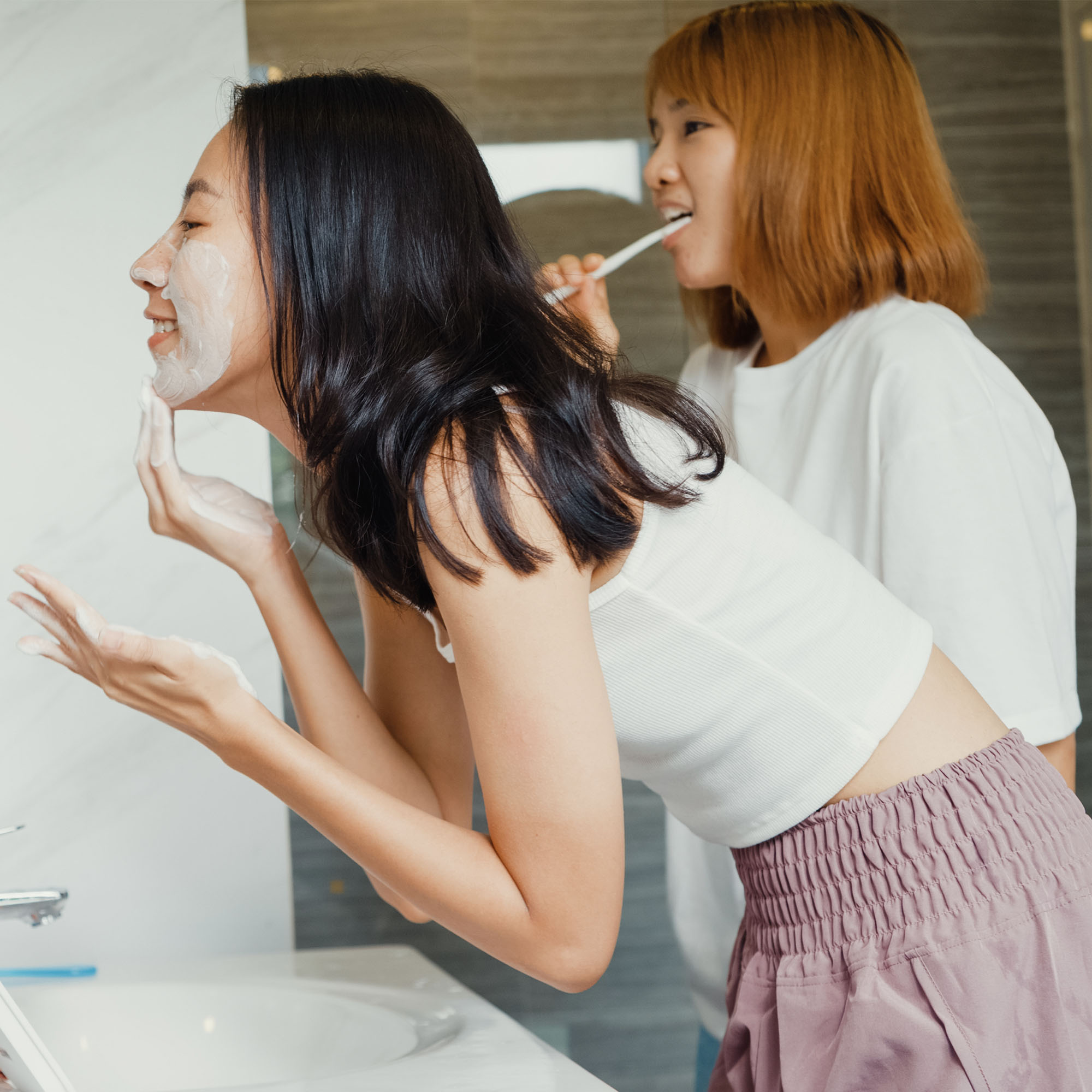 Two girls doing skincare in bathroom