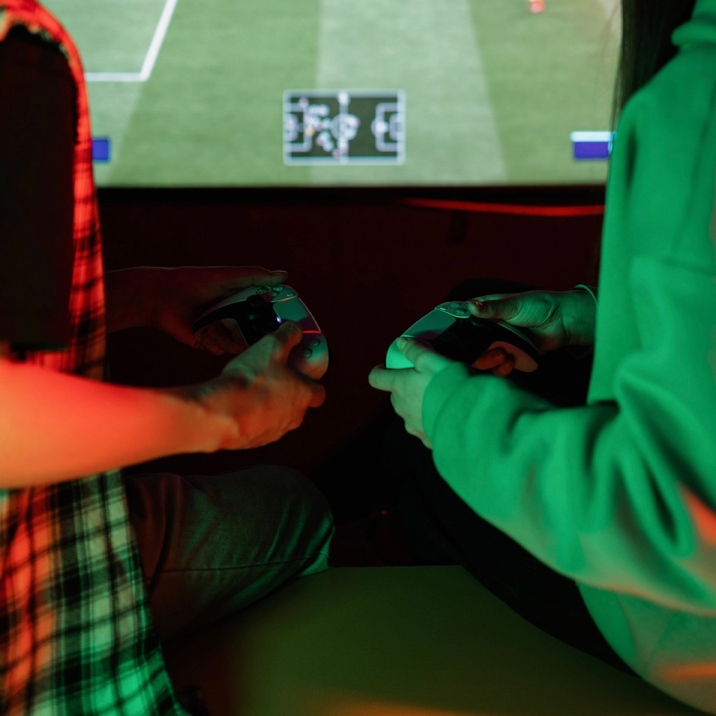 Two people playing FIFA on controllers